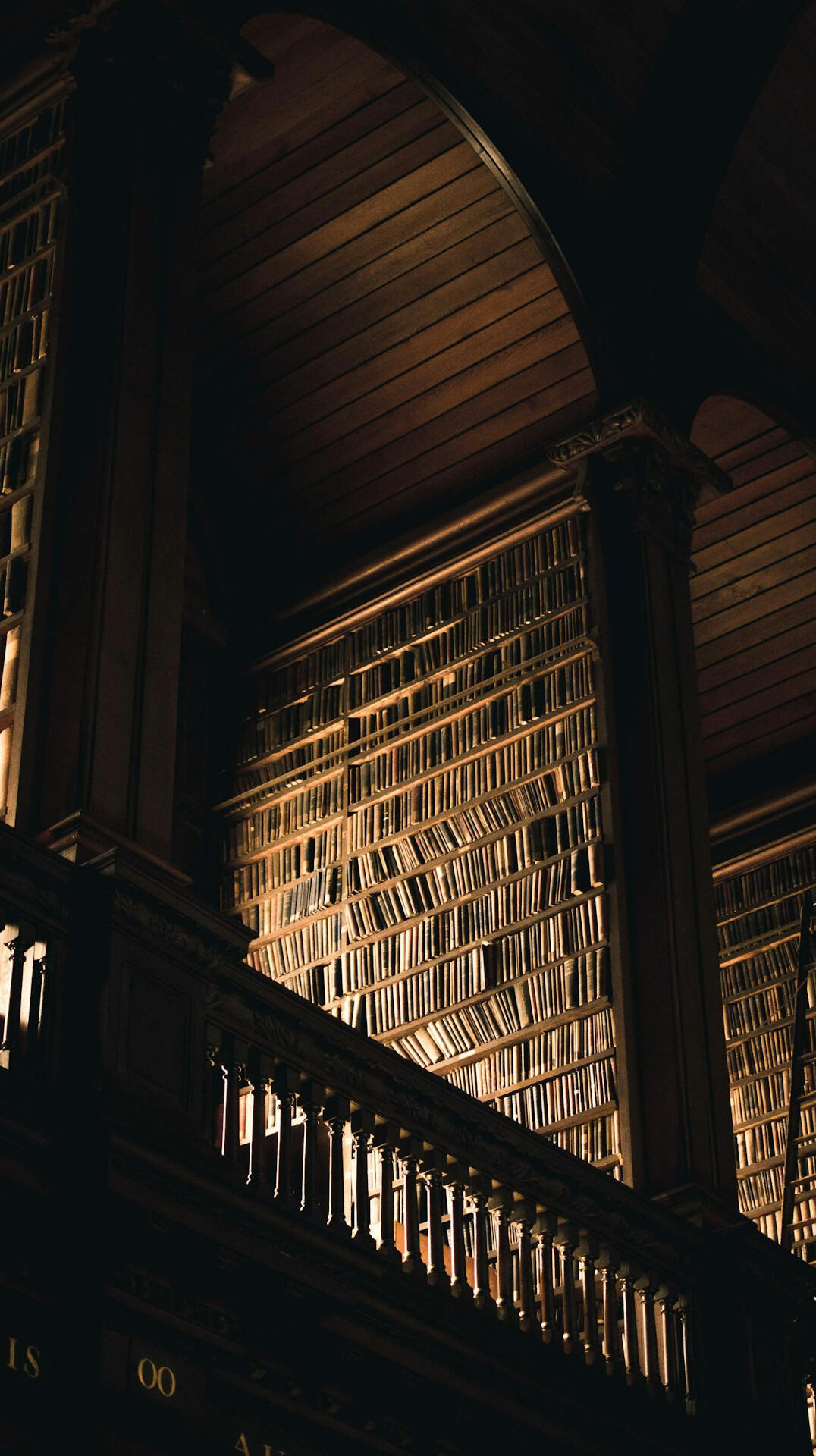Old library with tall wooden bookshelves and warm light